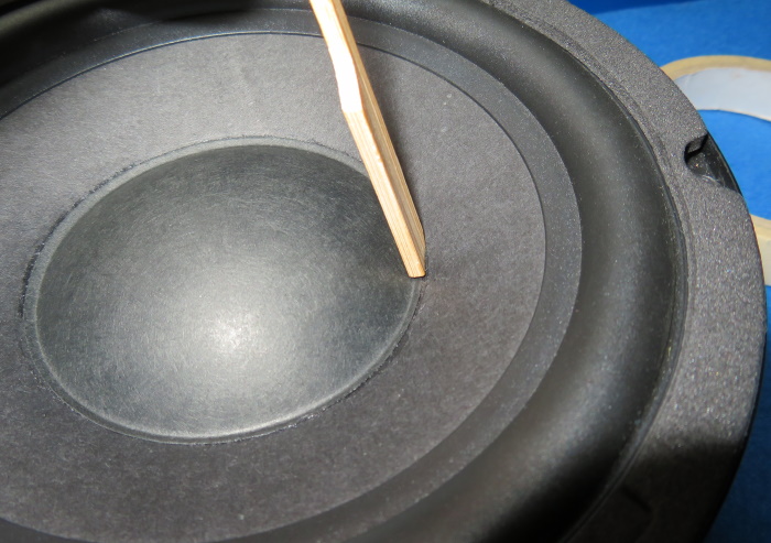 Ersatz der Lautsprecher-Staubkappe - Reiben / drücken Sie mit einem Holzspatel auf die Leimkante der Staubkappe.