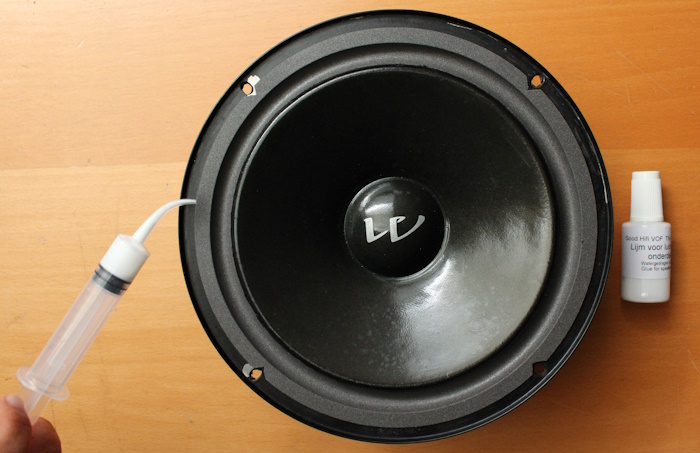 Breng lijm aan tussen het woofer frame en de foamrand